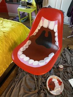 a chair that has been painted to look like a mouth with teeth on it, sitting in front of a bed