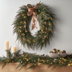 a christmas wreath with lights on top of a mantle