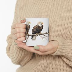 a woman holding a coffee mug with two bald eagles on it's front and back