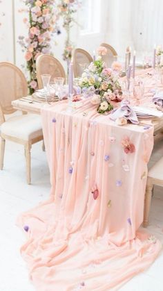 the table is set with pink and purple flowers, candles, and napkins on it