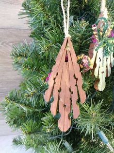 wooden ornaments hanging from a christmas tree with pine needles and flowers in the back ground