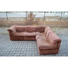 a brown sectional couch sitting on top of a brick floor