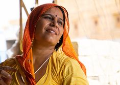 a woman wearing a yellow shirt and orange shawl is looking up at the sky