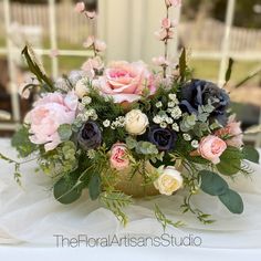 a vase filled with lots of flowers on top of a white table covered in greenery