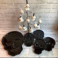 a group of black and white skull shaped trays next to a tree with skulls on it