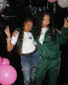 two young women standing next to each other in front of balloons