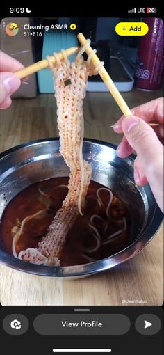 someone is holding chopsticks over a bowl of soup with noodles in the middle