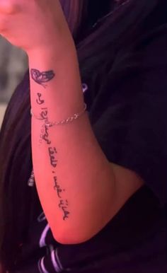 a woman with a tattoo on her arm holding a cell phone up to her ear