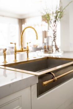 a kitchen sink with brass faucets and marble counter tops