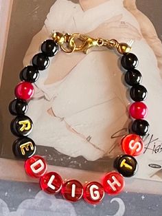 a red and black beaded bracelet with the word high written on it in gold