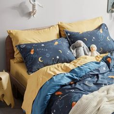 a bed with blue and yellow comforters in a bedroom next to a stuffed animal