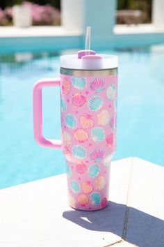 a pink and blue cup sitting next to a swimming pool