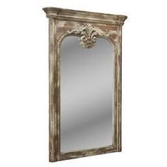 an antique mirror with ornate carvings on the top and bottom frame, hanging from a white wall