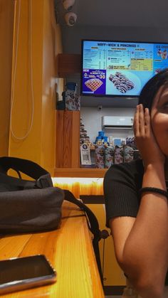 a woman sitting at a table in front of a tv with her hands to her face