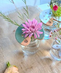 three vases filled with flowers sitting on top of a cloth covered tableclothed surface