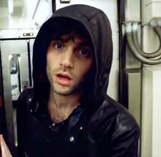 a man in a hoodie on a subway train looking at the camera and making a funny face