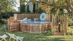 an outdoor hot tub in the middle of a yard with lounge chairs and tables around it