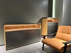 an orange chair sitting in front of a wooden counter next to a black and brown cabinet