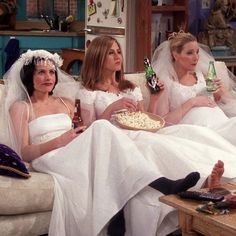 three brides sitting on a couch eating pizza