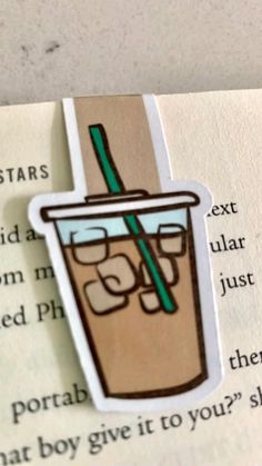 a close up of a book with a paper cut out of a drink on it