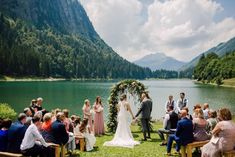 a couple getting married at the end of their wedding ceremony in front of a mountain lake