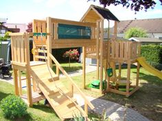 a wooden play set in the backyard with stairs leading up to it's roof