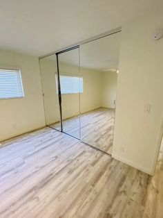 an empty room with wooden floors and mirrored doors on the walls is seen in this image