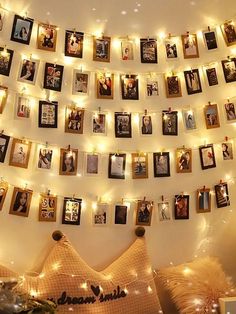 there are many pictures hanging on the wall with string lights around them and some decorations