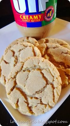 two cookies on a plate next to a jar of peanut butter