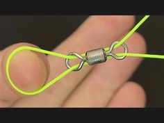 a hand holding a green string with a metal clasp on it