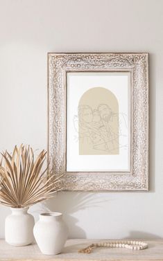 two white vases sitting on top of a wooden table next to a framed painting