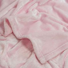 a pink blanket is laying on top of a white bed sheet and the sheets are folded down