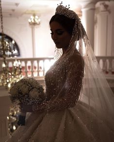 a woman in a wedding dress holding a bouquet and wearing a tiara with pearls on it