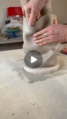 two hands are working on a clay vase