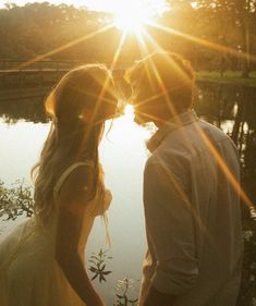 a man and woman standing next to each other in front of a body of water