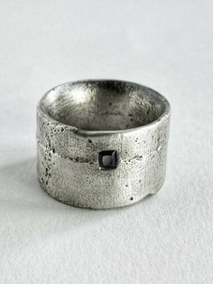 a close up of a ring on a white surface with a black diamond in the middle