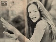 an old photo of a woman with long hair holding her hand out to the side