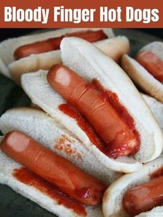 several hotdogs with ketchup on them are sitting in a black plate