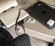 an apple laptop computer sitting on top of a desk next to a notebook and headphones