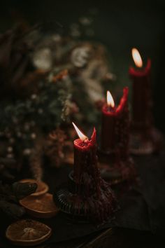 two red candles sitting on top of a table next to coins and other things in the background