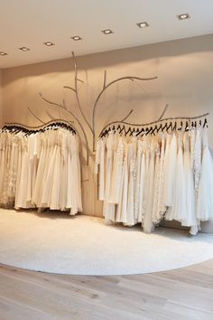 wedding gowns are displayed on racks in a bridal room with white carpet and wooden flooring