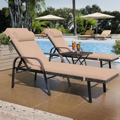 two lounge chairs next to a pool with umbrellas on the side and an empty table