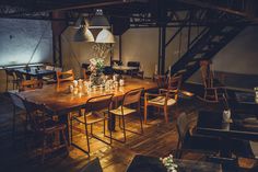 a wooden table surrounded by chairs and tables with flowers on them in an industrial setting