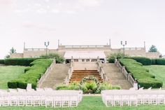 an outdoor ceremony setup with white chairs and steps leading up to the wedding venue on grass