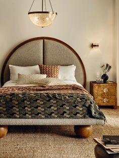 a bedroom with a bed, nightstands and two lamps hanging from the ceiling above it