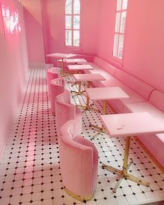 a pink room with long tables and chairs lined up against the wall in front of them