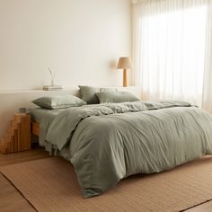 a large bed sitting in a bedroom next to a window with curtains on the windowsill