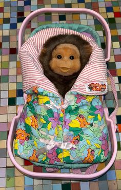 a stuffed monkey in a baby stroller on the ground with colorful tiles behind it