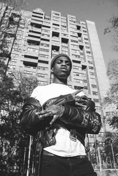 a black and white photo of a man in front of a tall building holding a glove