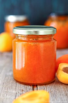 a jar filled with oranges sitting on top of a wooden table next to sliced oranges